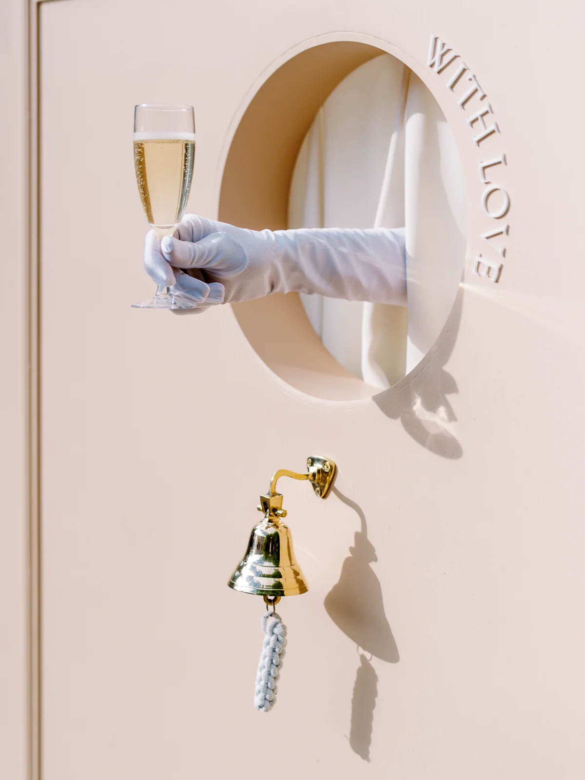 Hand in white glove serving champagne through a wall, wedding price.