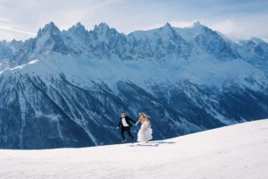 Couple sautant sur la neige capturé par un photographe mariage Saint Moritz devant les sommets enneigés.