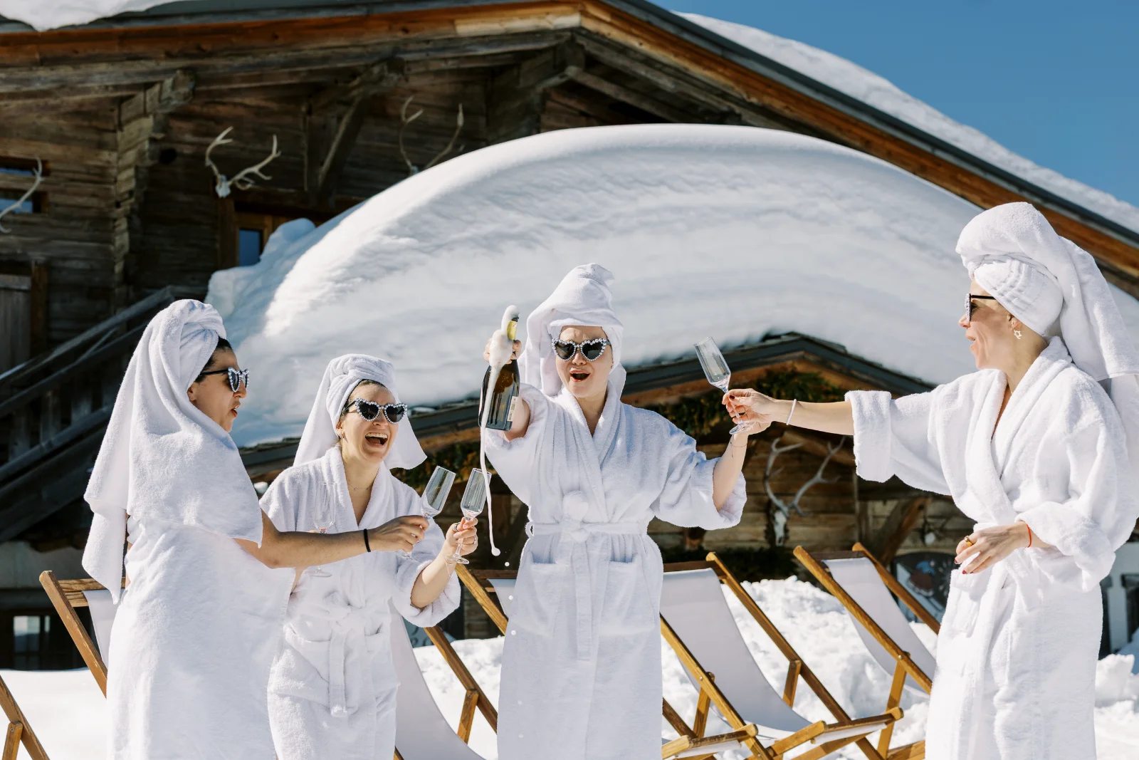 Amies en peignoir célébrant l'événement pour se marier à Saint Moritz devant un chalet enneigé.